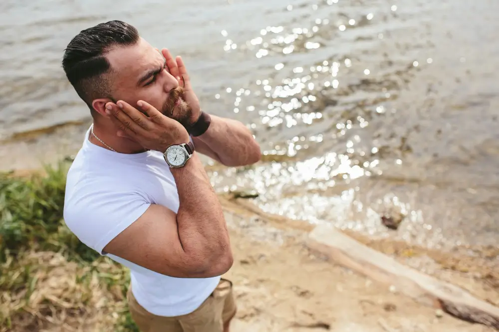 Fit and stylish man grooming by the water, embodying confidence, self-care, and the essence of summer scents for men.